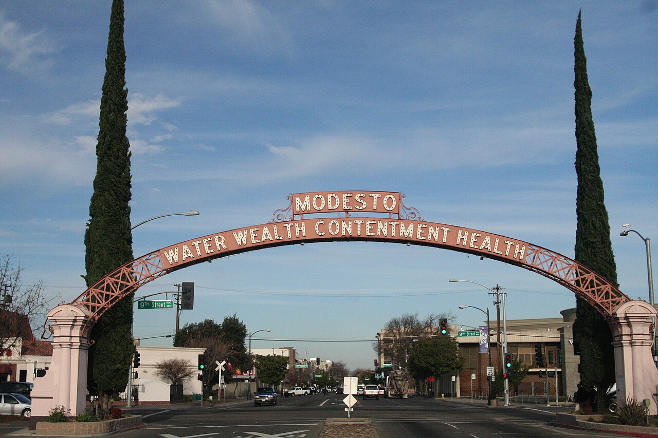 The Modesto Arch over I Street, lit at dusk — cover of WELCOME Modesto, the Modesto California city magazine